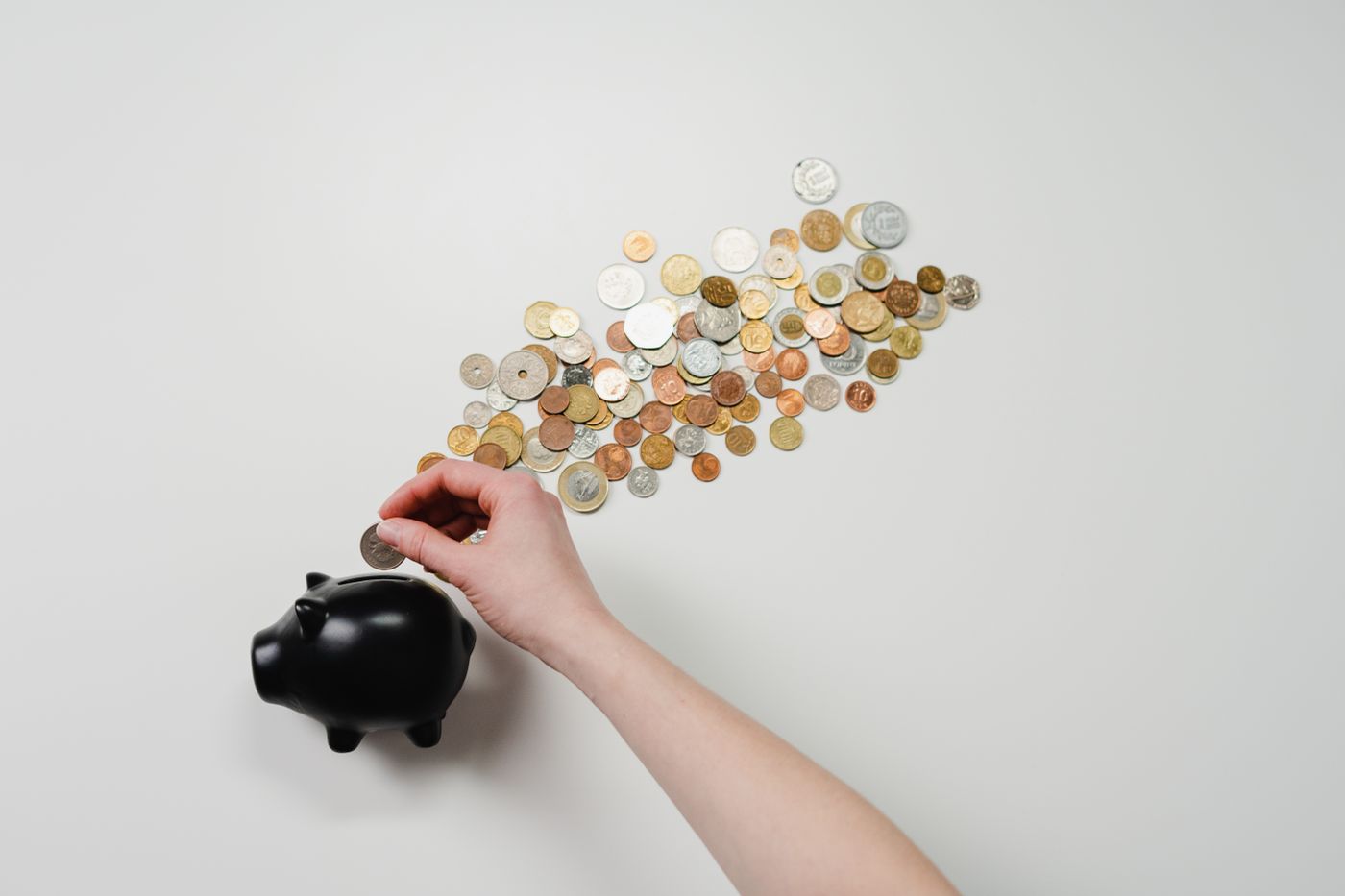 Mano che inserisce una moneta in un salvadanaio durante una pianificazione del risparmio