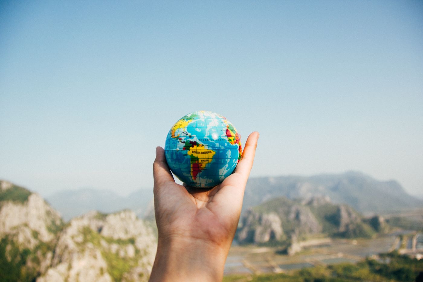 Mano che regge un piccolo globo durante la pianificazione di un viaggio internazionale