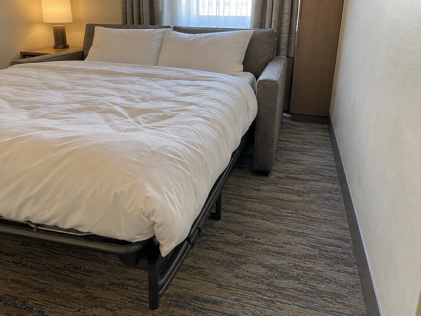 Divano letto aperto e passaggio laterale in una camera d’hotel