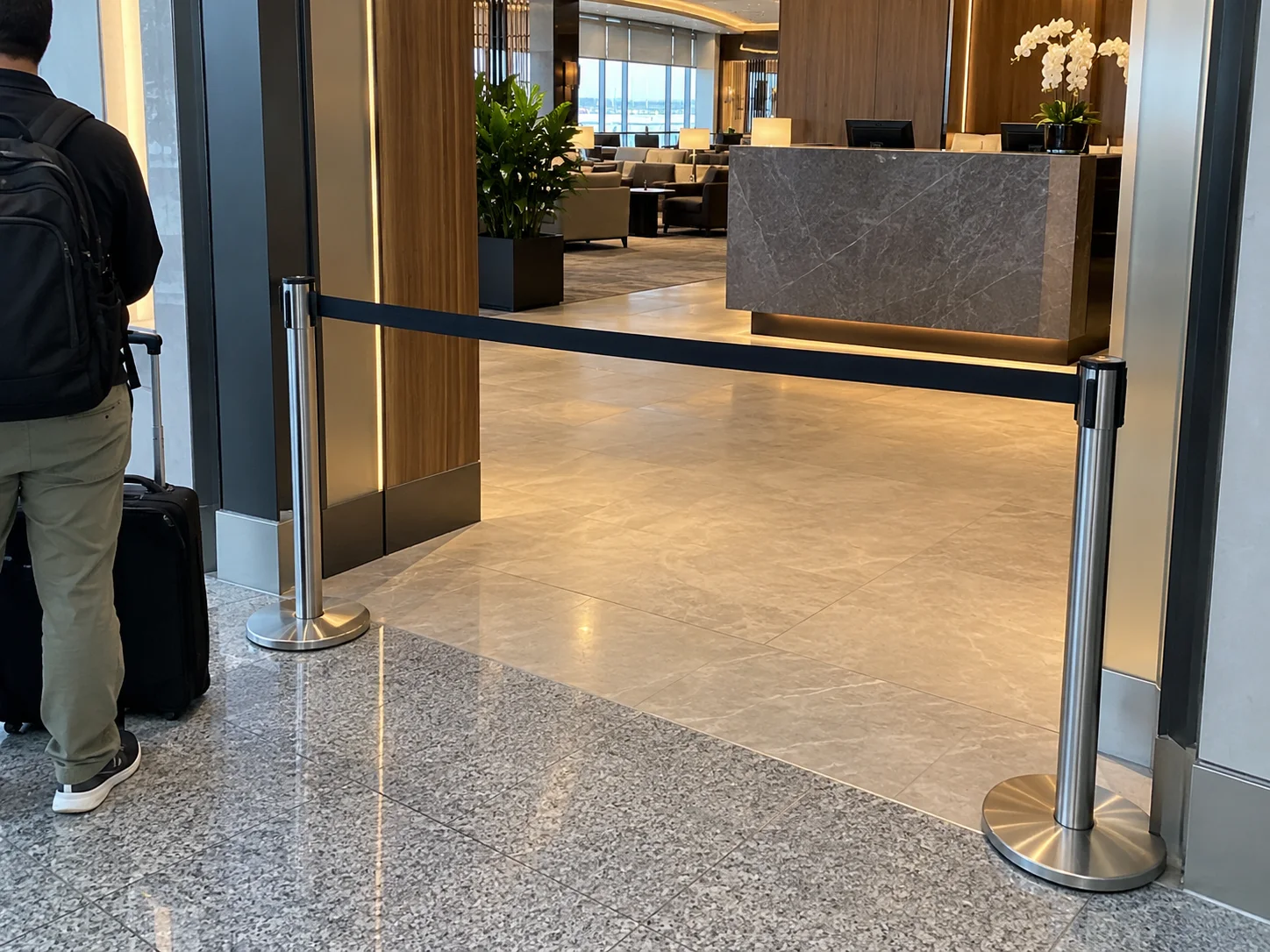 Ingresso di una lounge con barriera per la coda e un viaggiatore in attesa
