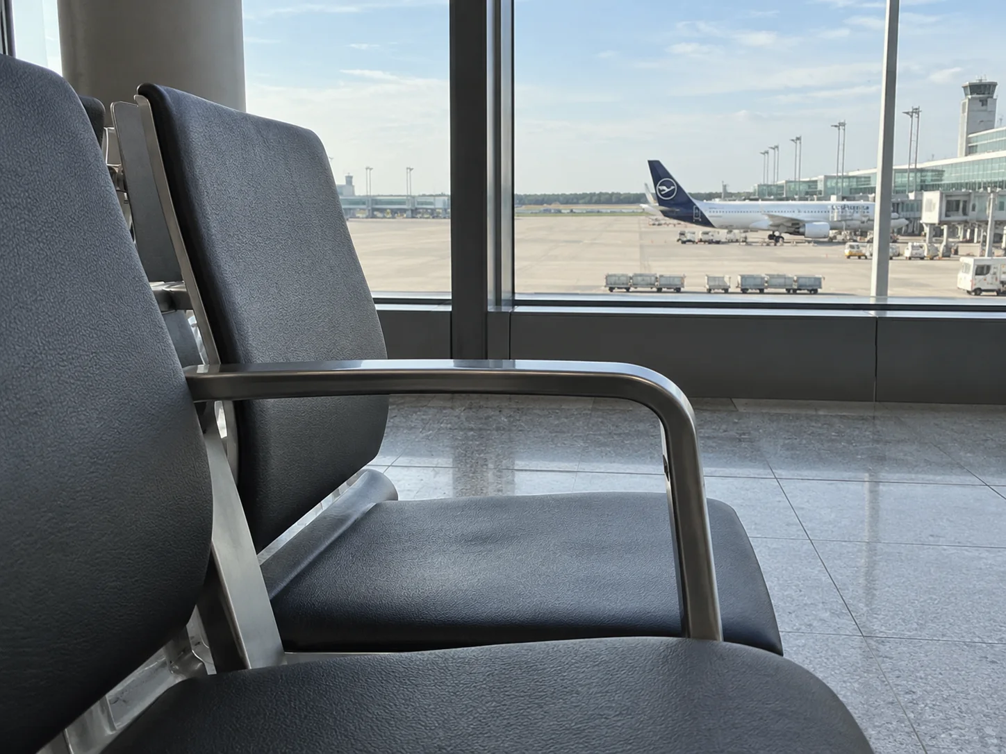 Sedute dell’area partenze davanti a una vetrata dell’aeroporto.