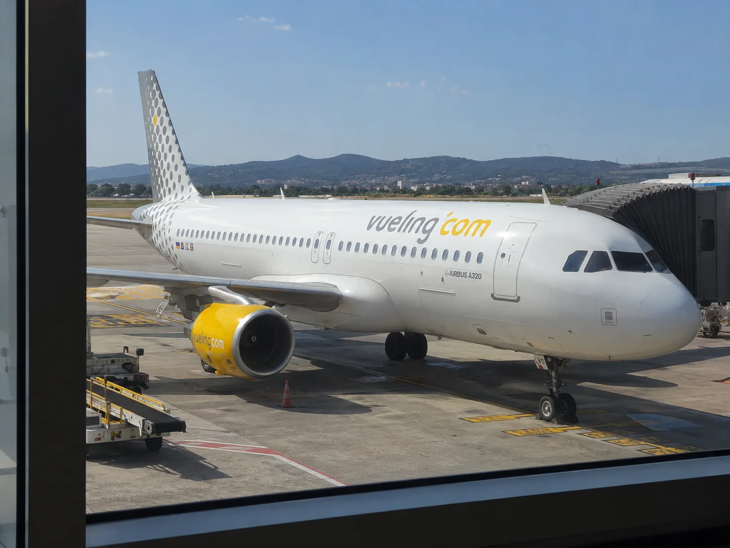 Aereo Vueling parcheggiato al gate visto dal terminal
